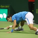 Novak Djokovic slides along the baseline in Doha