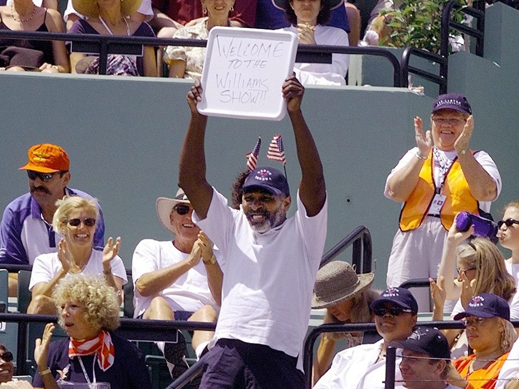 KEY BISCAYNE, UNITED STATES: Richard Williams holds up a sign reading "Welcome to the Williams Show" prior to the start of the women's final on 28 March 1999 between his daughters Venus and Serena (Photo: ROBERT SULLIVAN/AFP/Getty Images)